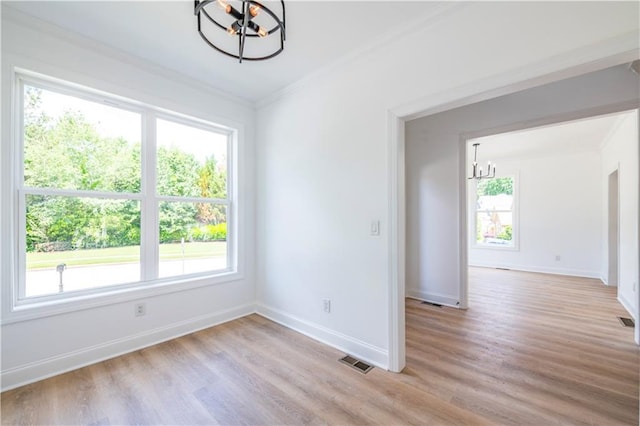 spare room featuring light wood-type flooring, an inviting chandelier, and ornamental molding