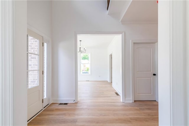 entrance foyer featuring light wood-type flooring, a notable chandelier, and crown molding