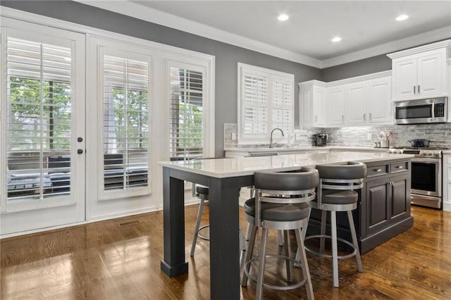 2362 Saint Davids Sq NW, Kennesaw, GA 30152 - kitchen featuring appliances with stainless steel finishes, white cabinets, a center island, dark wood-type flooring, and tasteful backsplash