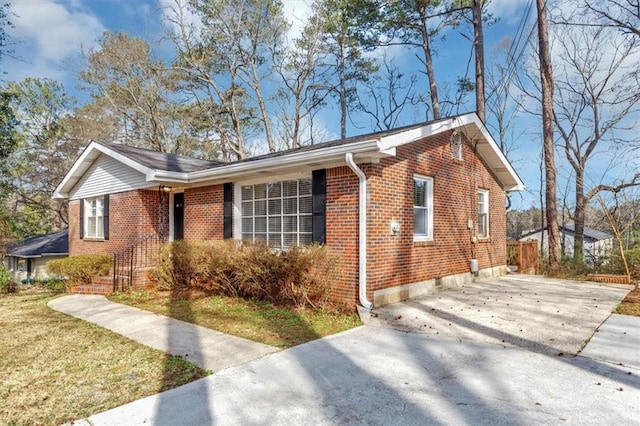 ranch-style house with brick siding, concrete driveway, and a front yard