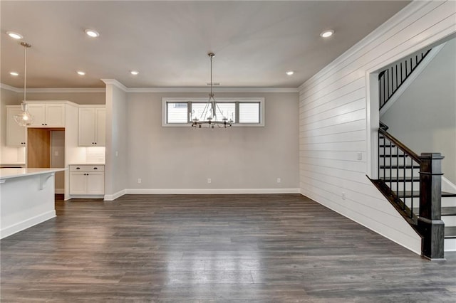 unfurnished dining area with crown molding, dark wood-style flooring, baseboards, stairway, and an inviting chandelier