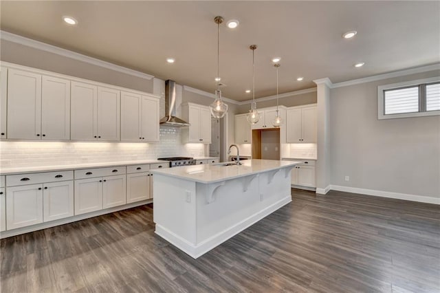 kitchen featuring wall chimney exhaust hood, white cabinetry, dark wood finished floors, and ornamental molding