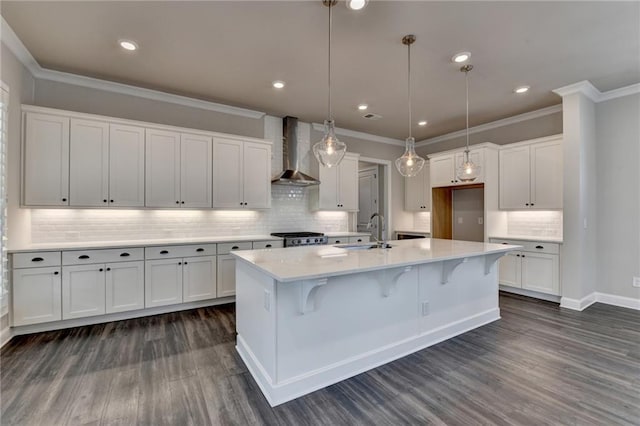 kitchen featuring wall chimney exhaust hood, white cabinets, a sink, and light countertops