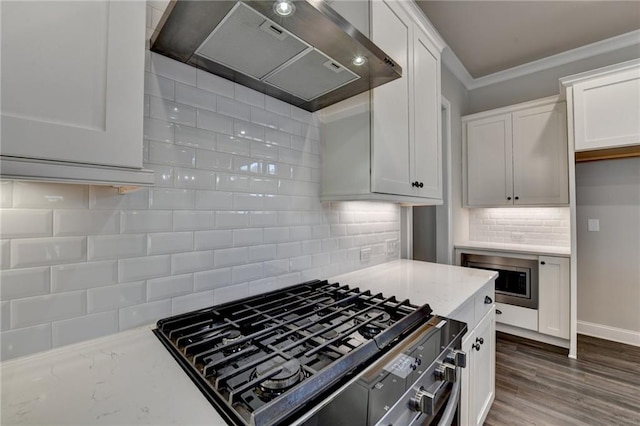 kitchen featuring light stone counters, wood finished floors, ornamental molding, wall chimney range hood, and stovetop