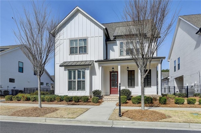 modern farmhouse style home with a porch, board and batten siding, a standing seam roof, fence, and metal roof