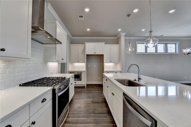 kitchen with white cabinets, appliances with stainless steel finishes, ornamental molding, wall chimney range hood, and a sink