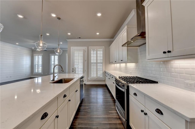 kitchen with decorative backsplash, dark wood-style floors, appliances with stainless steel finishes, wall chimney range hood, and a sink