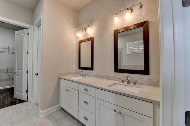 full bathroom with double vanity, tile patterned flooring, a sink, and baseboards