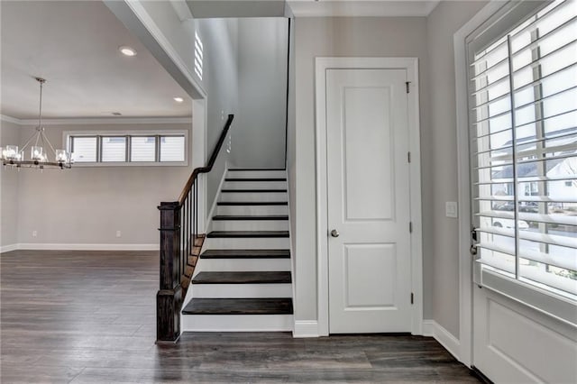 foyer entrance with a chandelier, wood finished floors, baseboards, ornamental molding, and stairway