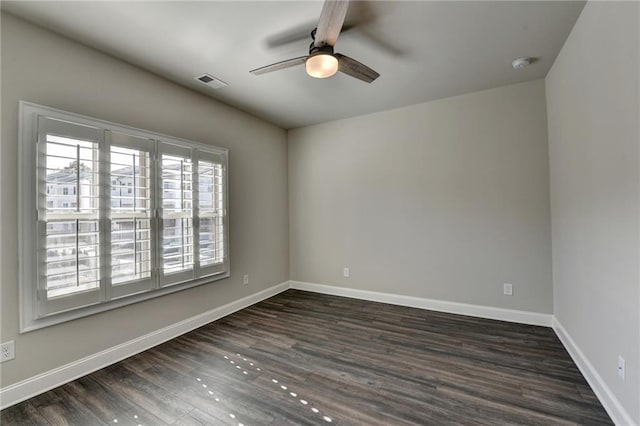 empty room featuring baseboards, visible vents, dark wood finished floors, and a ceiling fan