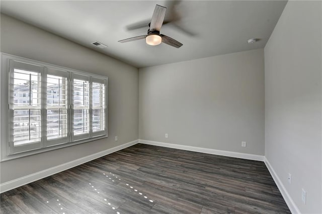 unfurnished room with dark wood-style floors, visible vents, ceiling fan, and baseboards