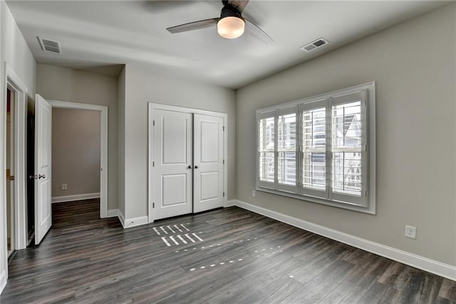 unfurnished bedroom with dark wood-type flooring, visible vents, and baseboards