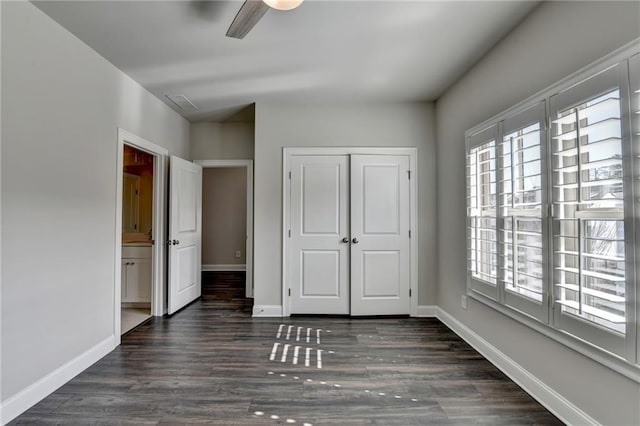 unfurnished bedroom featuring dark wood-style flooring, a closet, visible vents, a ceiling fan, and baseboards