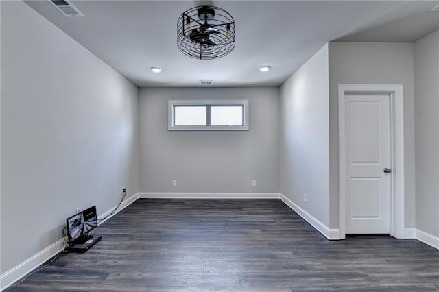 unfurnished room with baseboards, visible vents, and dark wood finished floors