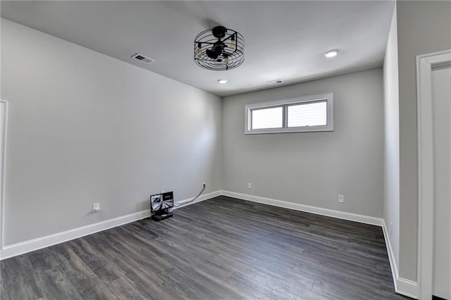 unfurnished room with dark wood-style flooring, visible vents, and baseboards