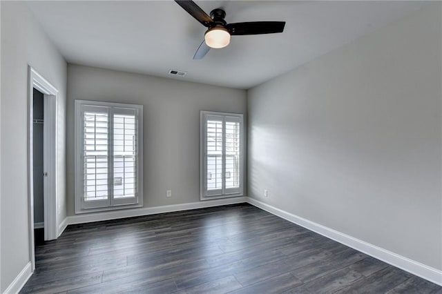 unfurnished room with dark wood-type flooring, visible vents, ceiling fan, and baseboards