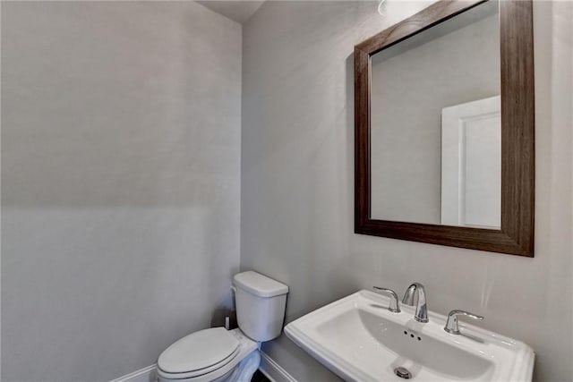 bathroom featuring baseboards, a sink, and toilet