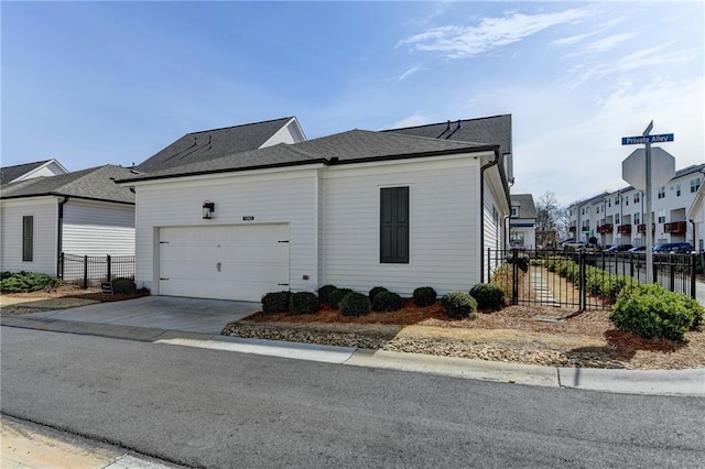 view of home's exterior with roof with shingles, an attached garage, fence, a residential view, and driveway