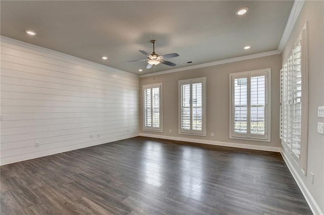 spare room with ornamental molding, dark wood-type flooring, a wealth of natural light, and baseboards