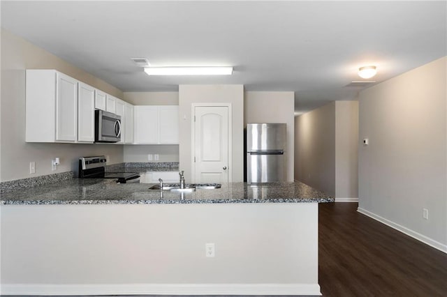 64 Middleton Ct, Chatsworth, GA 30705 - kitchen featuring appliances with stainless steel finishes, a peninsula, dark stone countertops, white cabinetry, and dark wood-style flooring