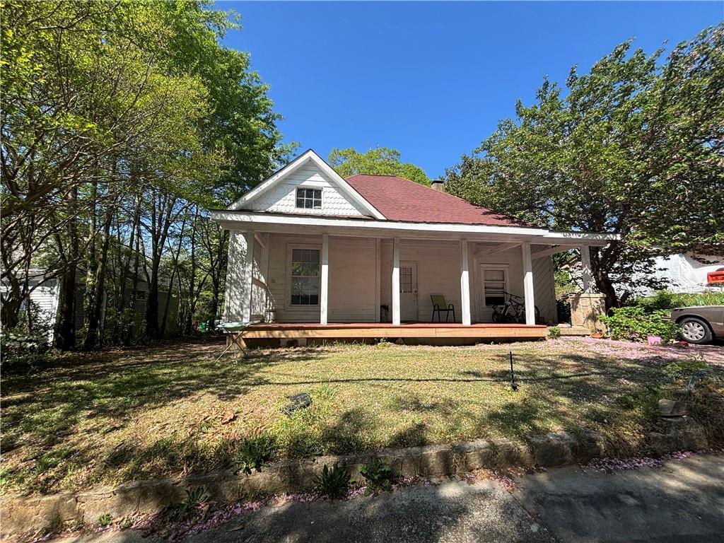 1090 Forest Ave, Stone Mountain, GA 30083 - country-style home with a porch, a front lawn, and a chimney