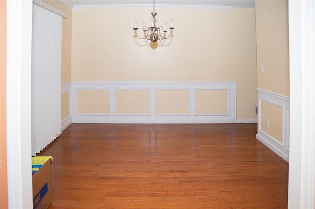 unfurnished room featuring crown molding, hardwood / wood-style floors, and an inviting chandelier