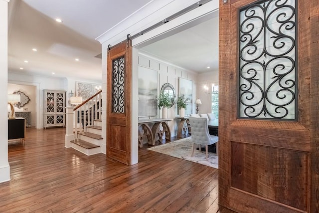 entryway with hardwood / wood-style flooring, a barn door, and ornamental molding