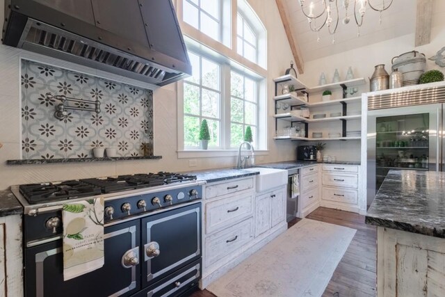 kitchen with dark stone counters, sink, exhaust hood, white cabinets, and light hardwood / wood-style floors