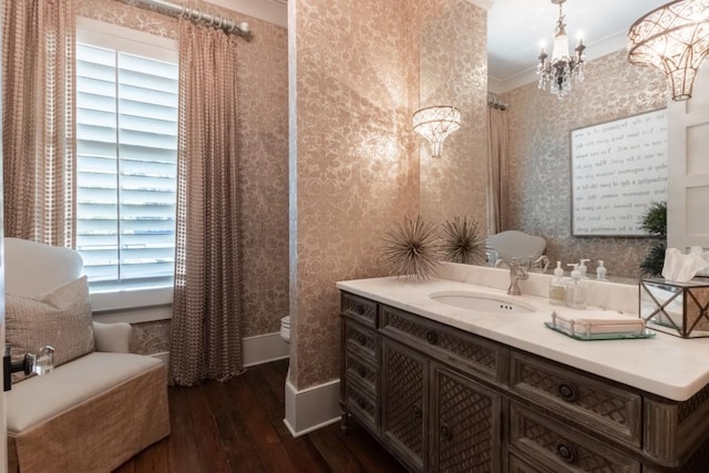 bathroom featuring ornamental molding, vanity, wood-type flooring, a chandelier, and toilet