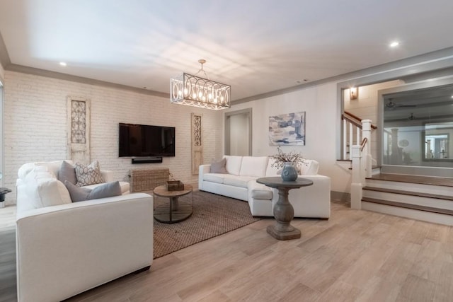 living room featuring a notable chandelier, light wood-type flooring, and brick wall