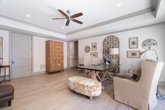 interior space with light hardwood / wood-style floors, ceiling fan, and a tray ceiling