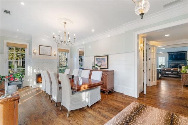 dining space with hardwood / wood-style floors, crown molding, and a chandelier