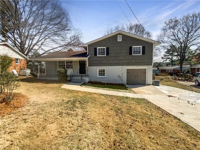 rear view of house with a garage, driveway, a yard, and covered porch