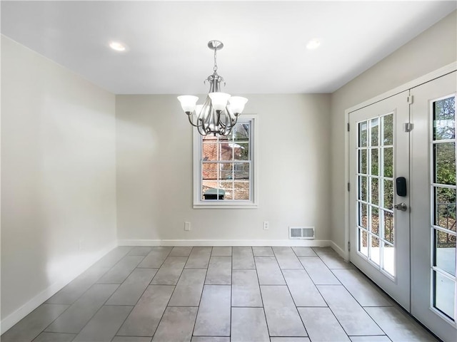 unfurnished dining area featuring plenty of natural light, visible vents, a notable chandelier, and baseboards