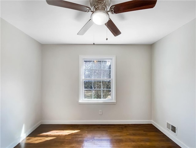 empty room featuring dark wood-style floors, ceiling fan, visible vents, and baseboards