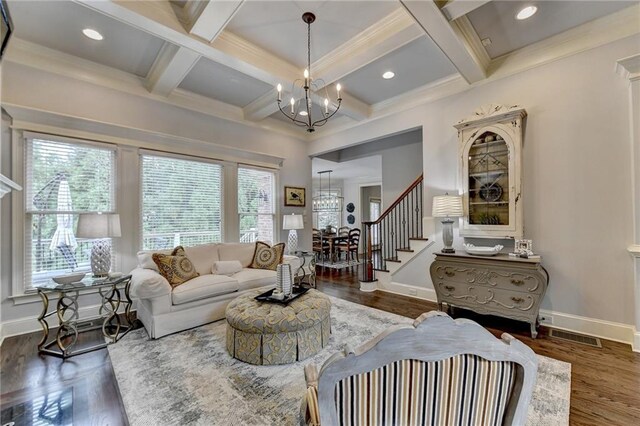 living room with dark wood-type flooring, coffered ceiling, crown molding, beamed ceiling, and a chandelier