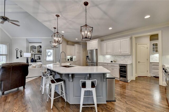 kitchen with a large island, sink, beverage cooler, stainless steel fridge with ice dispenser, and white cabinets