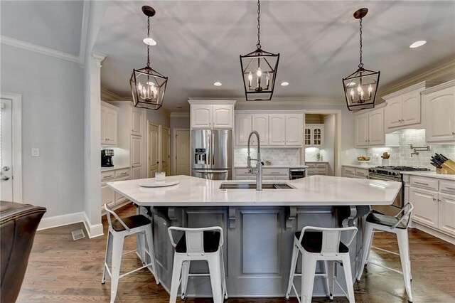 kitchen with white cabinets, appliances with stainless steel finishes, a breakfast bar area, and an island with sink