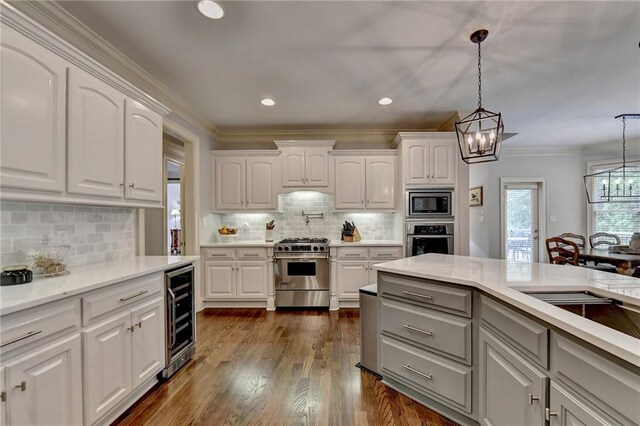 kitchen with hanging light fixtures, stainless steel appliances, white cabinetry, and beverage cooler