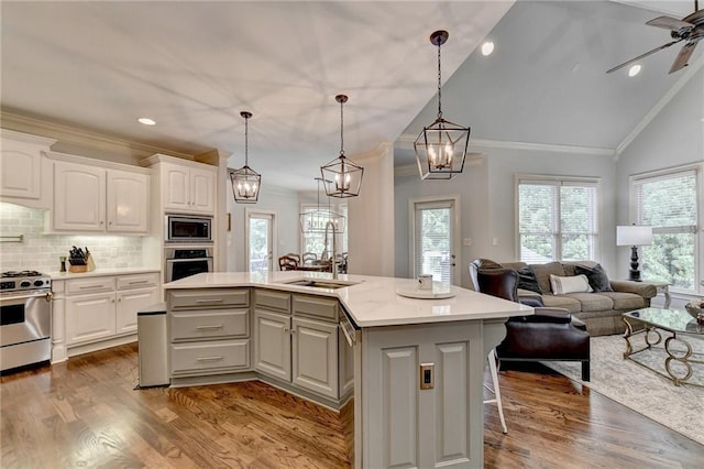 kitchen with sink, decorative backsplash, a center island with sink, white cabinets, and appliances with stainless steel finishes