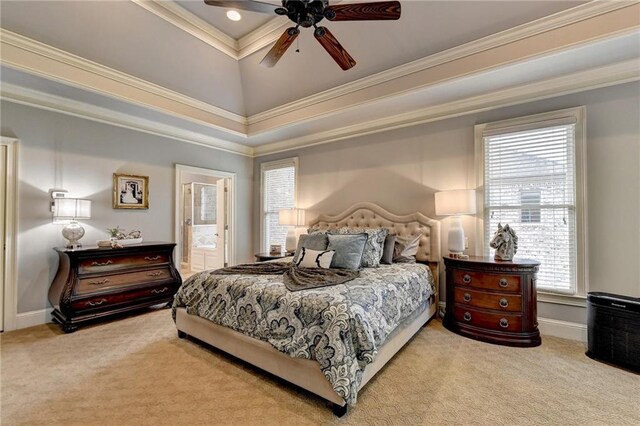 carpeted bedroom with connected bathroom, ceiling fan, a tray ceiling, multiple windows, and ornamental molding