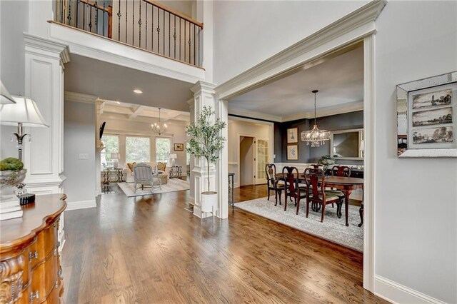 entryway with hardwood / wood-style floors, an inviting chandelier, coffered ceiling, crown molding, and beam ceiling