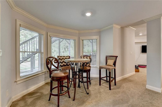 dining space with crown molding and light colored carpet