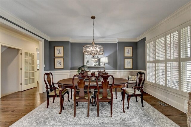 dining space featuring dark hardwood / wood-style flooring, ornamental molding, and a notable chandelier