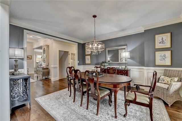 dining room with a chandelier, dark wood-type flooring, and crown molding