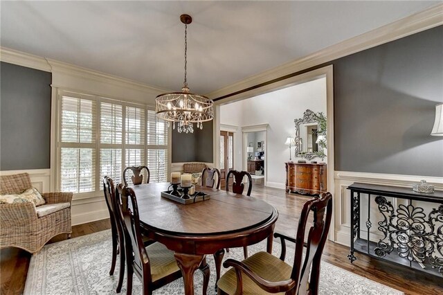 dining space with crown molding, an inviting chandelier, and hardwood / wood-style flooring