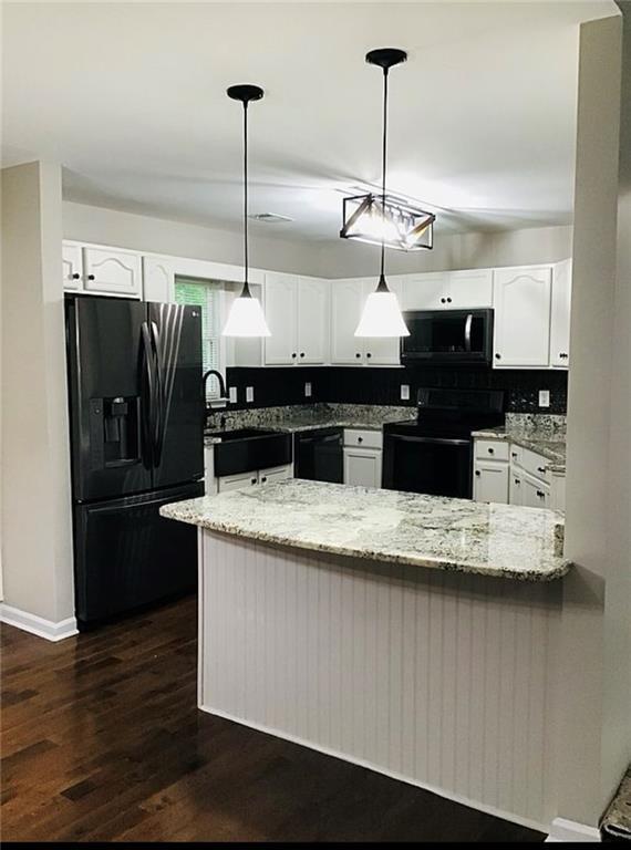 3535 Cameron Cir, Gainesville, GA 30506 - kitchen featuring black appliances, a peninsula, light stone countertops, and white cabinetry