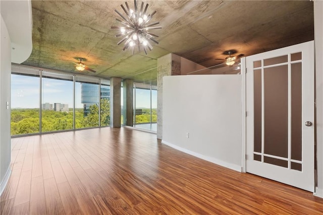 unfurnished room featuring expansive windows, a chandelier, and hardwood / wood-style flooring