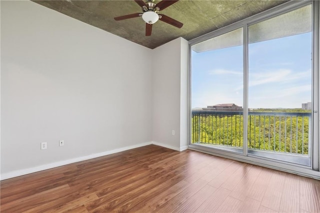 unfurnished room featuring hardwood / wood-style floors, ceiling fan, and a wall of windows