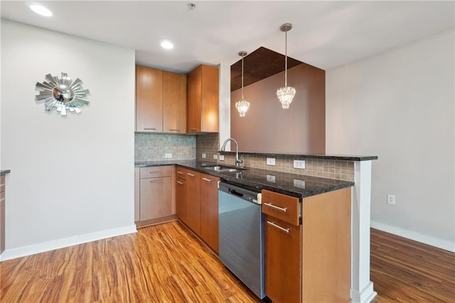 kitchen featuring tasteful backsplash, sink, decorative light fixtures, dishwasher, and light hardwood / wood-style floors